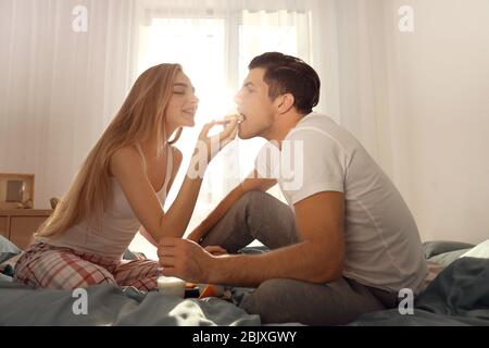 Ein junges, reizendes Paar, das im Bett gefrühstückt hat Stockfoto