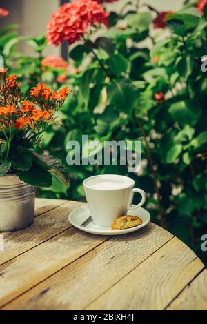 Tasse Milch mit Blumenstrauß über Holztisch. Traditionelle gesunde Bio-Lebensmittel-Konzept. Stockfoto