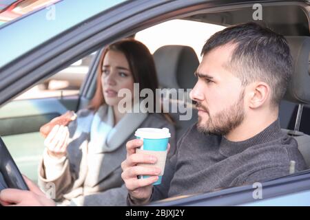 Junges Paar, das während des Staus im Auto einen Snack hat Stockfoto