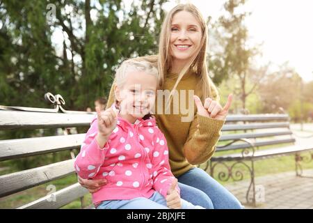 Wenig taubstumme Mädchen und ihre Verwendung von Gebärdensprache im Freien Mutter Stockfoto