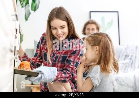 Junge Frau und ihre kleine Tochter Backen leckere Muffins zu Hause Stockfoto