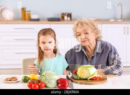 Süße kleine Mädchen mit Großmutter Vorbereitung Gemüse Salat in der Küche Stockfoto