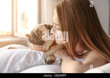 Morgen schöne junge Frau mit niedlichen Mops Hund im Schlafzimmer Stockfoto