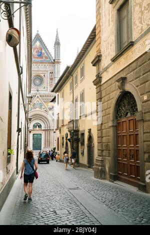 Touristen gehen die schmale Straße hinunter, die zum Dom führt, Italiens kühnster und beeindruckendster romanischer gotischer Dom aus dem Jahr 1290, der aus dem Jahr 1945 stammt Stockfoto