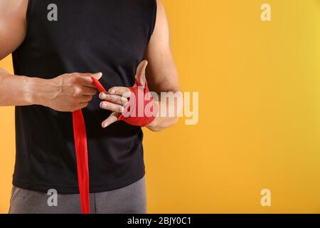 Sportlicher junger Mann Anwendung Armbänder gegen Farbe Hintergrund Stockfoto