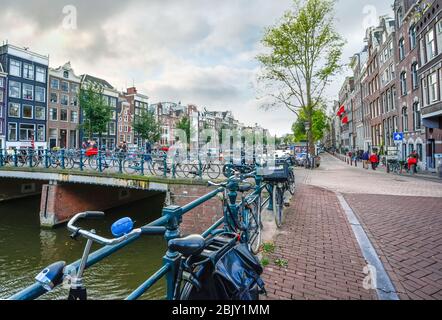 Fahrräder parken am Kanal und auf einer Brücke an einem bewölkten Herbsttag in Amsterdam Niederlande Stockfoto