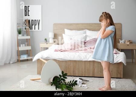 Kleines Mädchen in Zimmer mit überschnittenen Zimmerpflanze und Papier Stücke auf dem Teppich Stockfoto