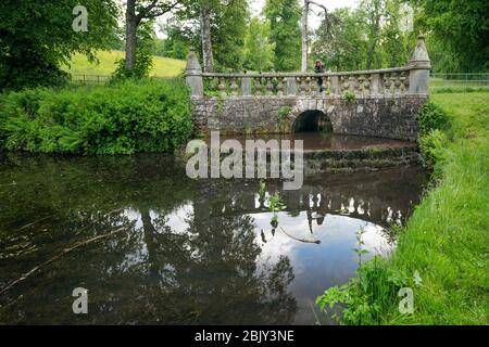 Eine Frau steht auf einer Steinbrücke mit Blick auf einen Teich in der Landschaft außerhalb des kleinen mittelalterlichen Dorf, Falkland, Fife, Schottland, Großbritannien, Europa Stockfoto