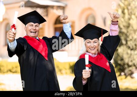 Gerne reifes Paar im Bachelor Roben im Freien Stockfoto