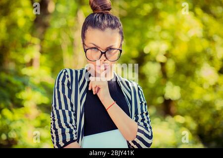 Junge schöne Brünette Frau mit Zeigefinger auf den Lippen zeigt Zeichen der Stille, draußen in einem grünen Park als Hintergrund. Stockfoto