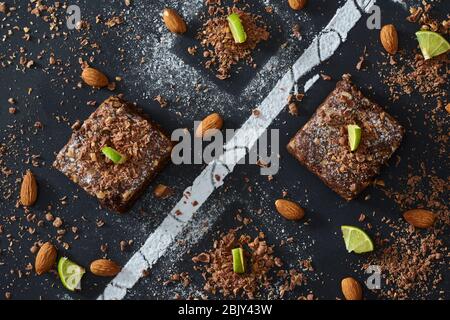 Schokoladenbrownies mit Zitronen und Mandeln in schwarzer Tabelle mit Zucker Stockfoto