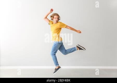 Hübscher junger Mann tanzen gegen weiße Wand Stockfoto