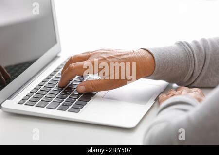 Ältere Frau mit modernen Laptop auf weißer Tisch, Nahaufnahme Stockfoto