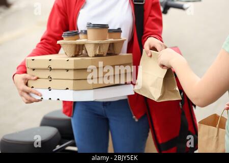 Frau nehmen um von Kurier von Food Delivery Service im Freien Stockfoto