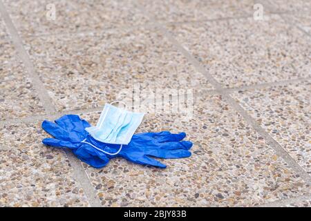 Gebrauchte Nitril medizinische Handschuhe und chirurgische Maske liegen auf dem Boden Stockfoto