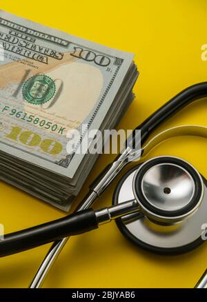 Stapel von 100 Dollar Scheine und stethoscopeÂ auf gelb backgroundÂ Stockfoto