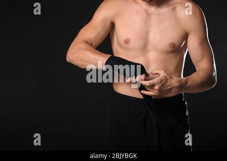 Starke männliche Boxer Anwendung Armbänder gegen den dunklen Hintergrund Stockfoto