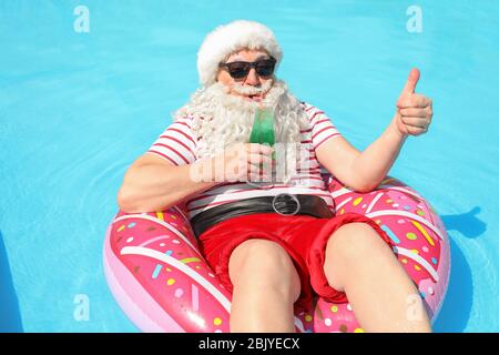 Santa Claus entspannend auf aufblasbaren Ring im Schwimmbad Stockfoto