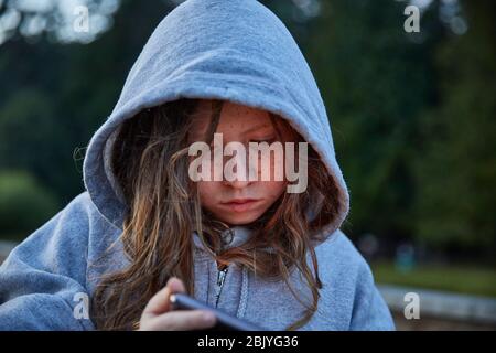 Mädchen im Hoodie mit Telefon Stockfoto