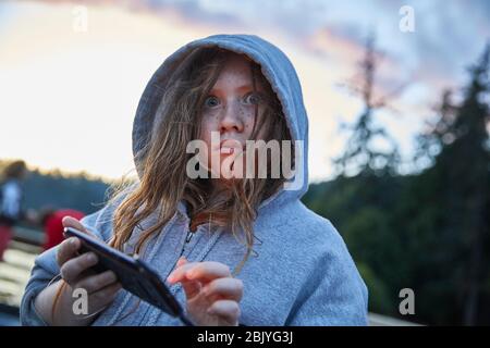 Mädchen im Hoodie mit Telefon Stockfoto