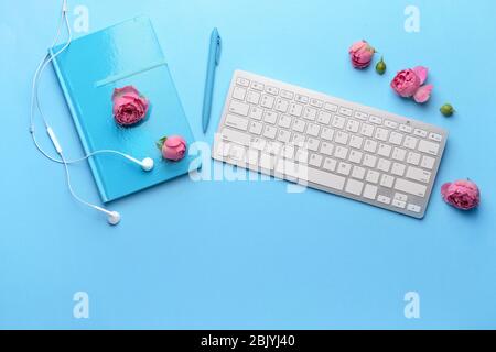 Moderne Computer Tastatur mit Briefpapier und Kopfhörer auf farbigen Hintergrund Stockfoto