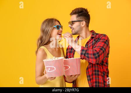 Junges Paar essen Popcorn auf farbigen Hintergrund Stockfoto