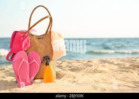 Beutel mit flip-flops, Badebekleidung, Handtuch, Sonnenbrille und Kosmetik auf Sand Strand Stockfoto