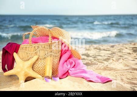 Beutel mit Seesternen, Badeanzug, Hut, Sonnenbrille und Kosmetik auf Sand Strand Stockfoto