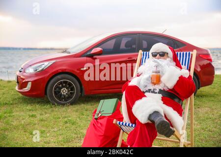 Cool Santa Claus mit Cocktail ruht auf Riverside Stockfoto