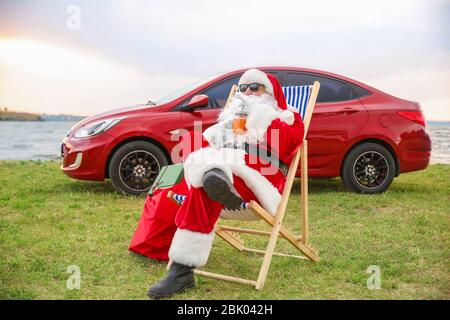 Cool Santa Claus mit Cocktail ruht auf Riverside Stockfoto