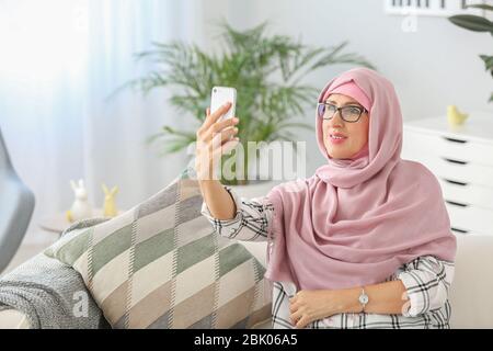 Schönen muslimischen Frau mittleren Alters mit Handy zu Hause Stockfoto