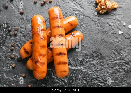 Leckere gegrillte Würstchen auf dunklem Hintergrund Stockfoto