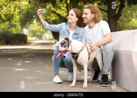 Junges Paar mit niedlichen Hund selfie in Park Stockfoto