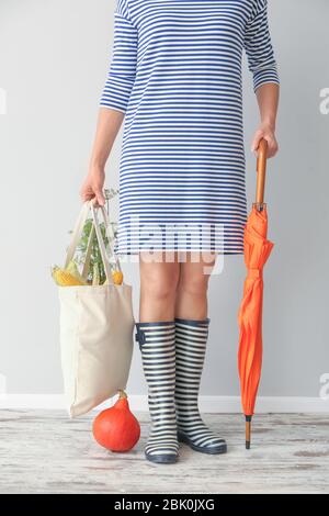Frau mit eco Tasche mit Produkten, die in der Nähe von hellen Wand Stockfoto