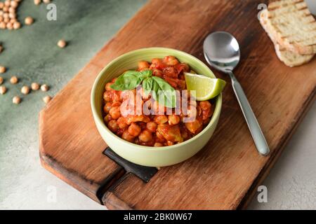 Schüssel mit leckerem Kichererbse in Tomatensauce auf Tisch Stockfoto