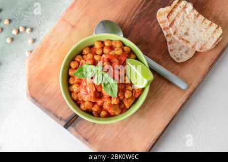 Schüssel mit leckerem Kichererbse in Tomatensauce auf Tisch Stockfoto