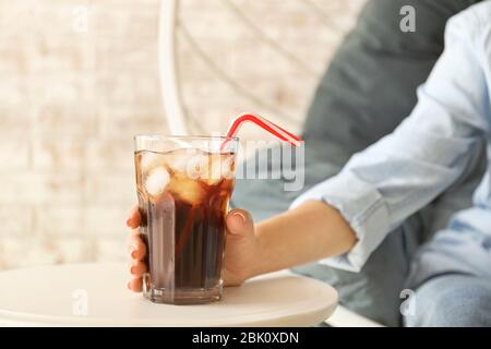 Frau unter Glas kalten Cola aus Tabelle Stockfoto