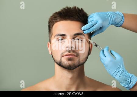 Schöner Mann empfangen Füller Einspritzung in Farbe Hintergrund Stockfoto