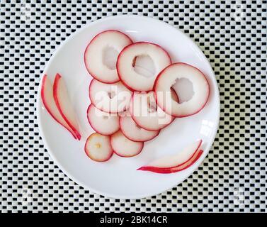 Scheiben Rosenobst in einem Teller auf einer weißen Oberfläche Stockfoto