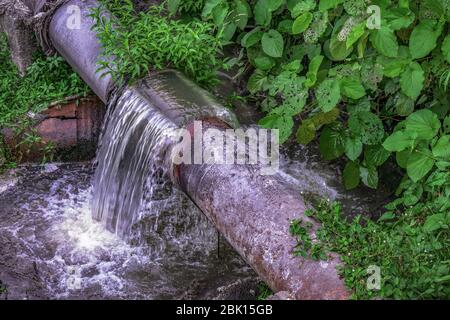 Kaputtes, schmutziges Wasserrohr, das viel schmutziges Wasser ausgießt Stockfoto