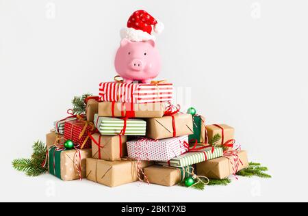 Sparschwein in weihnachtsmann Hut. Weihnachtsgeschenkboxen. Weißer Hintergrund. Das Konzept des Sparens. Stockfoto