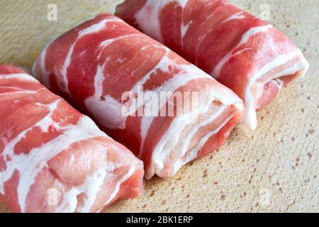 Nahaufnahme von drei holländischen Slavinken auf einem Holzbrett. Slavink ist ein niederländisches Fleischgericht, das aus in Speck gehülltem Hackfleisch besteht. Stockfoto