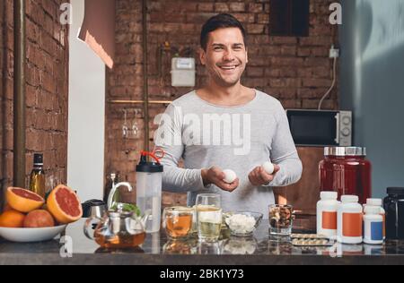 Fröhlicher Mann bereitet sein eigenes nahrhaftes Frühstück Stockfoto