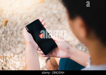 RAYONG, THAILAND, APR 12,2020: Ein Mann, der das Samsung Galaxy Note Smartphone mit Youtube Logo auf dem Handy-Bildschirm hält. YouTube ist die beliebteste Online-Seite Stockfoto