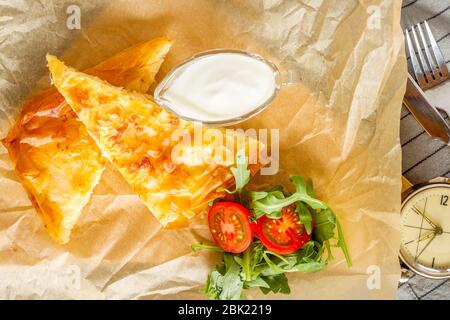 Käsekuchen mit einer Schüssel Joghurt und Rucola-Salat. Stockfoto