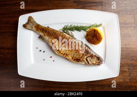 Gegrillte Forelle mit ähneltem und Zitrone auf einem weißen Teller in einem Restaurant serviert Stockfoto