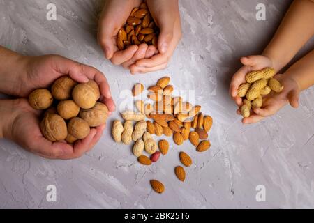 Haselnüsse, Walnüsse, Cashews, Mandeln in Kinderhänden Draufsicht Stockfoto