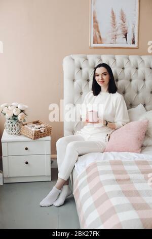 Hübsche Frau, die morgens Tee oder Kaffee im Schlafzimmer genießt. Stockfoto