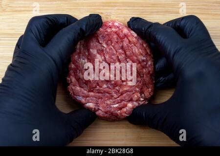 Rohes Rindfleisch Burger Kochen auf natürlichen Bambus Holz Schneidebrett Hintergrund close-up. Draufsicht. Stockfoto