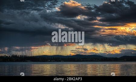 Gewitterwolken und Regen bei Sonnenuntergang über dem Varese See im Frühjahr Stockfoto